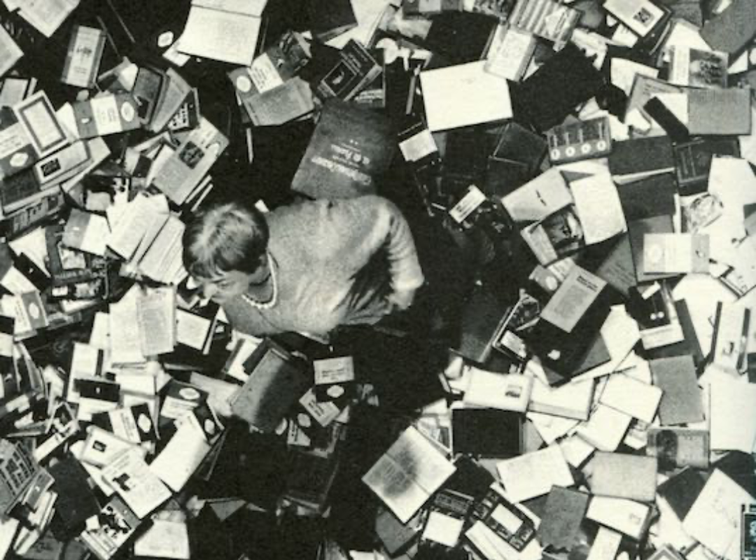 A screenshot from Fahrenheit 451, showing a person surrounded by countless books on the floor around them.