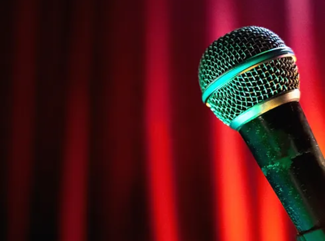 Image of a microphone with a dark red curtain in the background