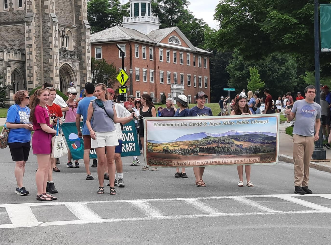 Library staff, trustees and volunteers marching in the July 4th parade, bearing the library's banner.