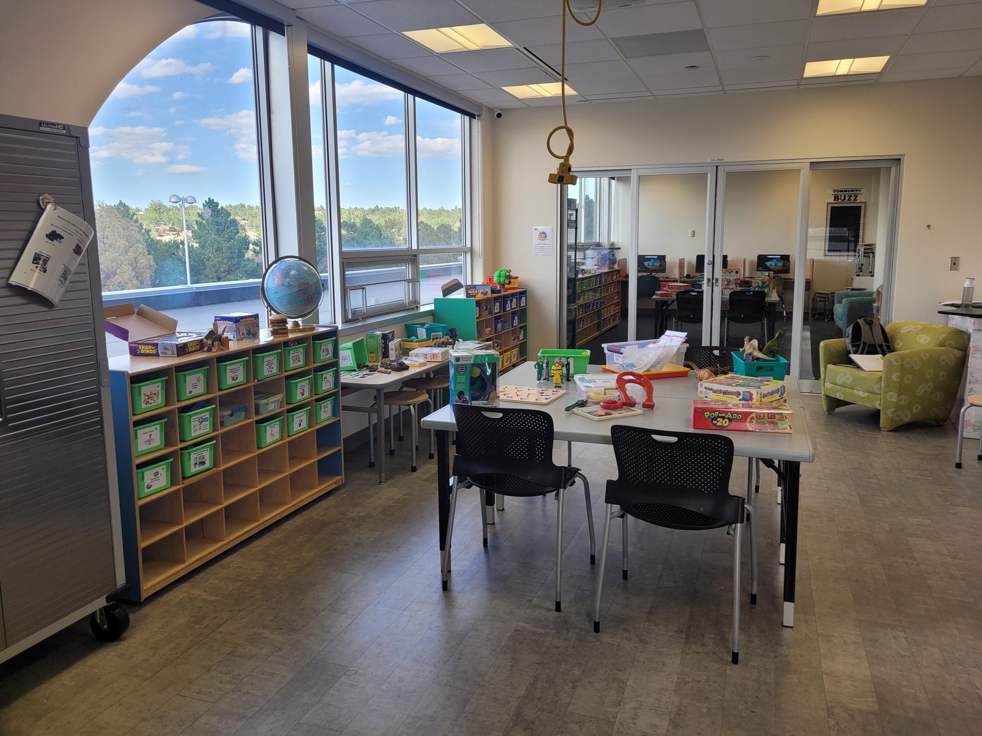 A photograph of the Educational Resource Center showing tables and chairs and shelves filled with toys.