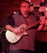 Photo of musician Ron Averill holding guitar during performance