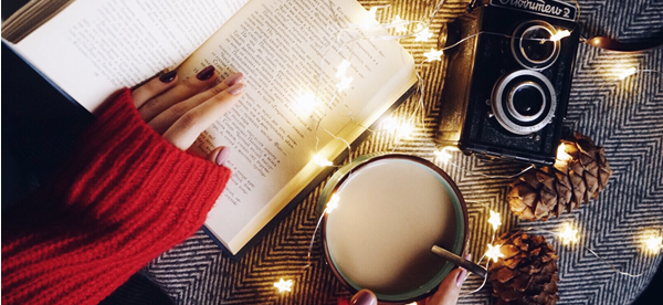 Header image with book, twinkle lights on a cozy blanket. 
