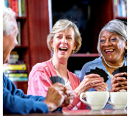 Link to Coffee and Games event will open in an external site and in a new tab or window. Image of three adults laughing, playing card games, and drinking coffee.