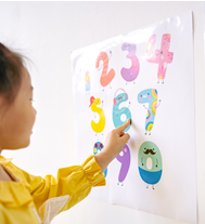 Image of a young girl in a yellow dress tracing numbers on a wall.