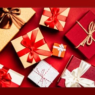 Small Christmas presents wrapped in gold and white paper on a red background.  This image will go to a calendar search in an external site and will open in a new tab or window.