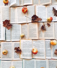 Open books with fall leaves and freshly picked apples.